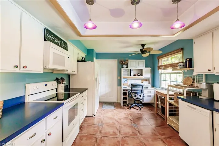 Kitchen with white cabinetry, white appliances, a raised ceiling, ceiling fan, and decorative light fixtures