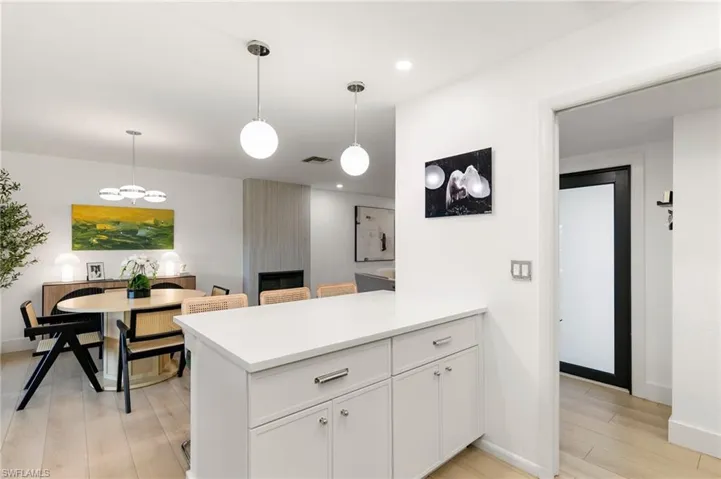 Kitchen featuring a large fireplace, a peninsula, visible vents, white cabinetry, and light wood-type flooring