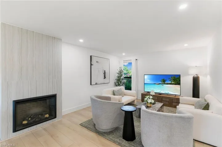 Living area featuring a fireplace, baseboards, wood finished floors, and recessed lighting