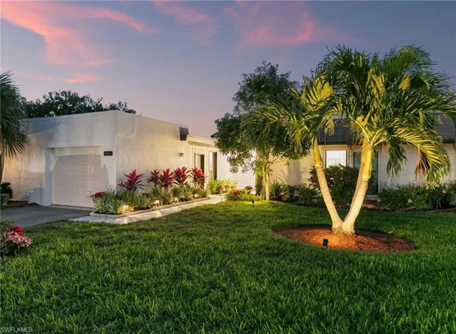 View of front of house featuring a garage, aphalt driveway, a lawn, and stucco siding