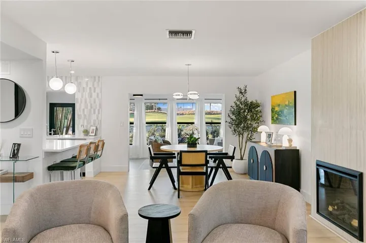 Dining area with light wood-style flooring, visible vents, baseboards, and a glass covered fireplace