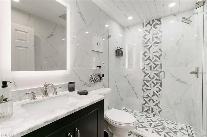Bathroom with a marble finish shower, visible vents, toilet, vanity, and recessed lighting