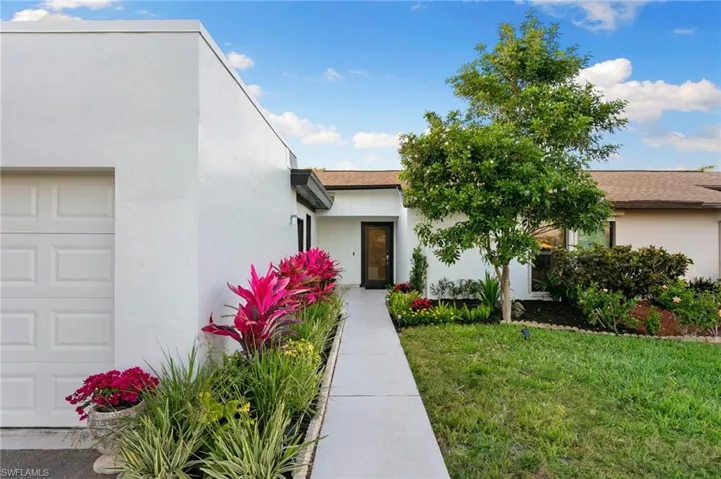 View of front facade with an attached garage, a front yard, and stucco siding