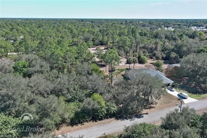 Aerial view of property and surrounding area with a heavily wooded area