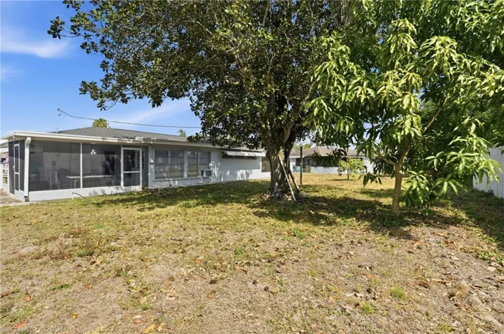 Rear view of property with a sunroom and a yard