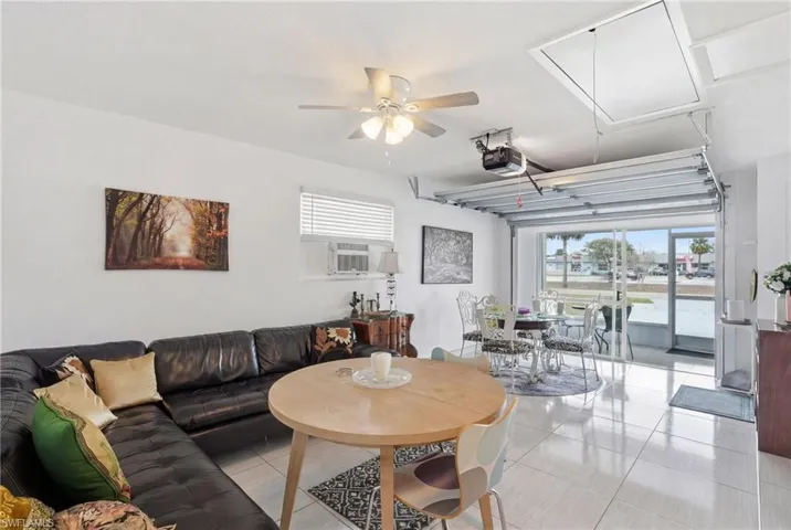 Living area featuring ceiling fan, light tile patterned floors, and cooling unit