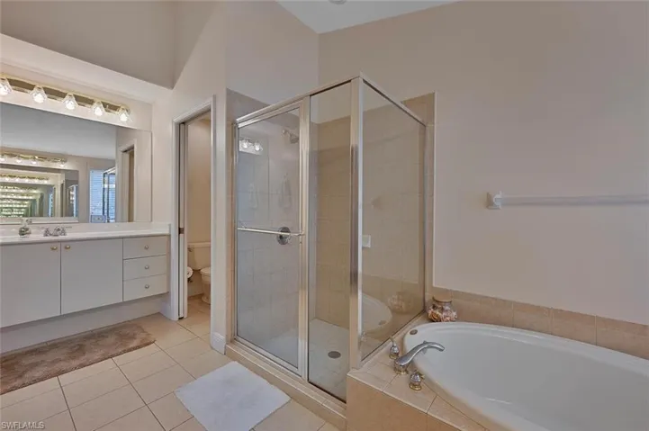 Full bathroom featuring toilet, shower with separate bathtub, vanity, and tile patterned floors