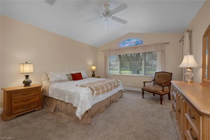 Bedroom with vaulted ceiling, light carpet, and ceiling fan