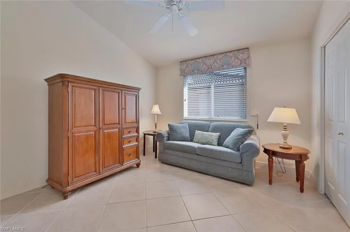 Tiled living room featuring ceiling fan and vaulted ceiling