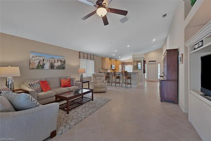 Living room with lofted ceiling, ceiling fan, and light tile patterned floors