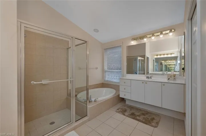 Bathroom with vanity, lofted ceiling, independent shower and bath, and tile patterned floors