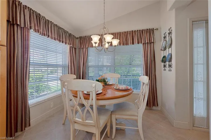 Tiled dining space with a chandelier and vaulted ceiling