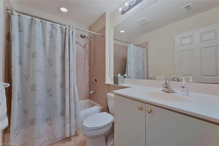 Full bathroom with a textured ceiling, toilet, vanity, shower / tub combo with curtain, and tile patterned flooring