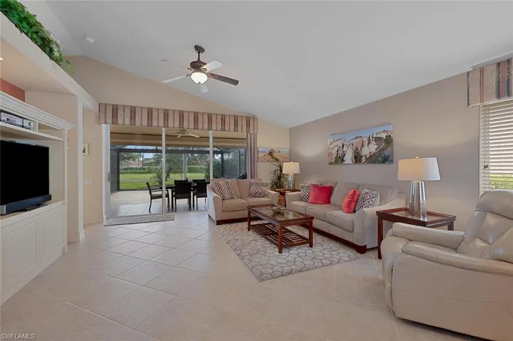 Living room with ceiling fan, high vaulted ceiling, and light tile patterned floors