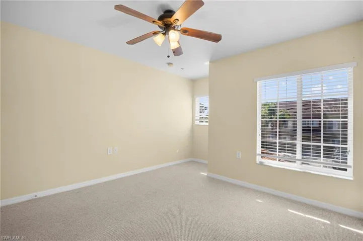 Carpeted empty room featuring baseboards and ceiling fan