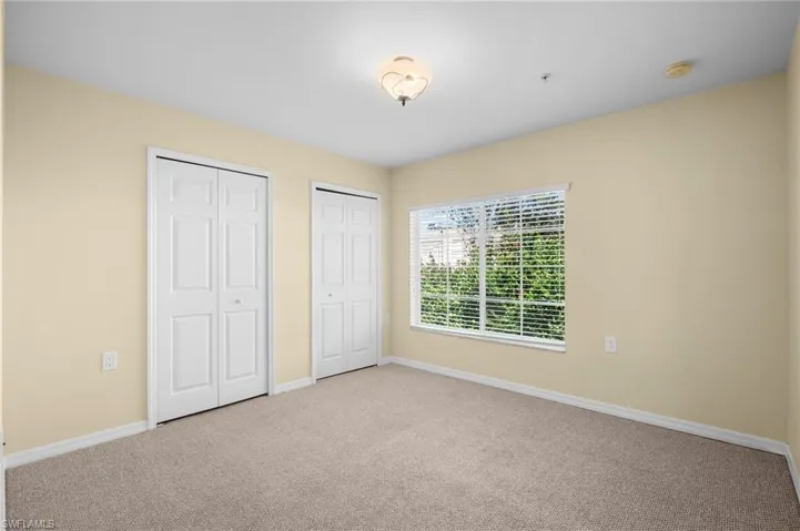 Unfurnished bedroom featuring multiple closets and carpet flooring