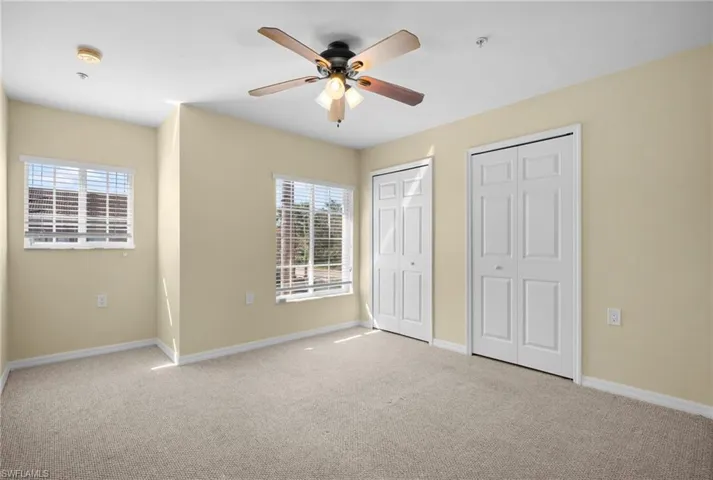 Unfurnished bedroom with multiple closets, carpet, and ceiling fan
