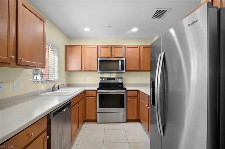 Kitchen with stainless steel appliances, wood finish cabinets, light countertops, and recessed lighting