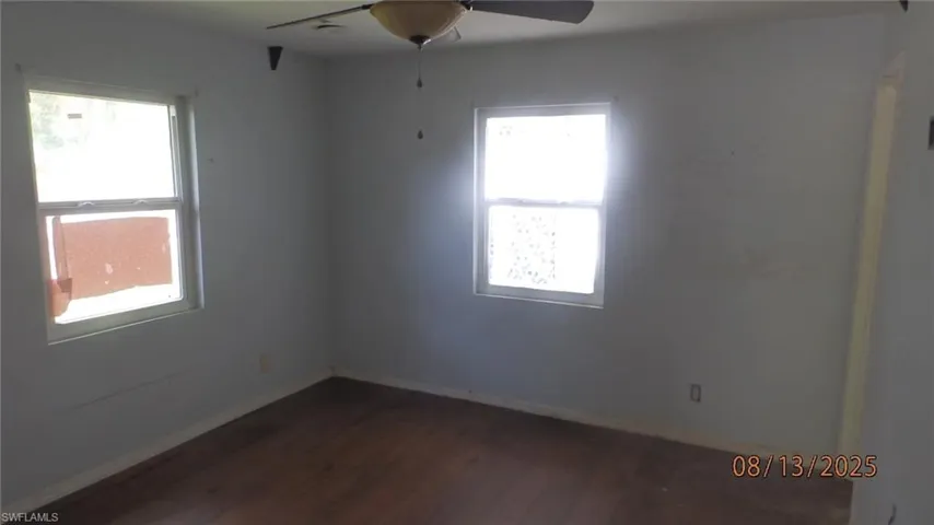 Empty room with dark wood finished floors and ceiling fan