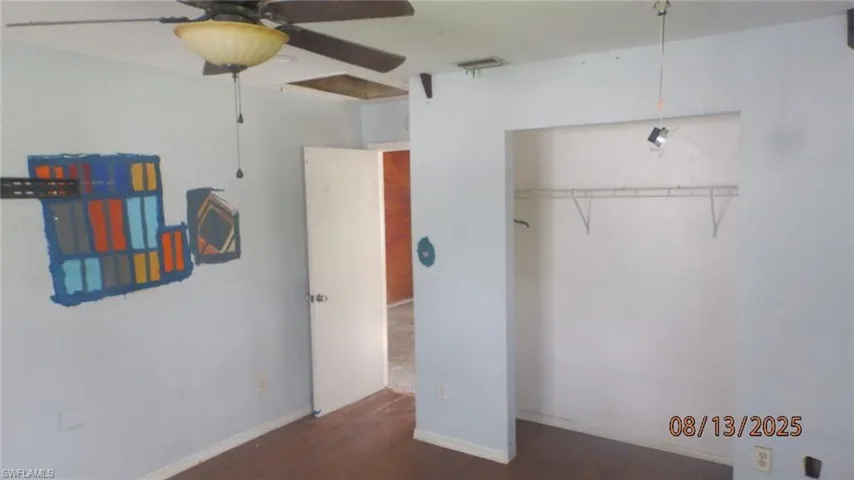 Unfurnished bedroom with dark wood-style flooring, a ceiling fan, and a closet