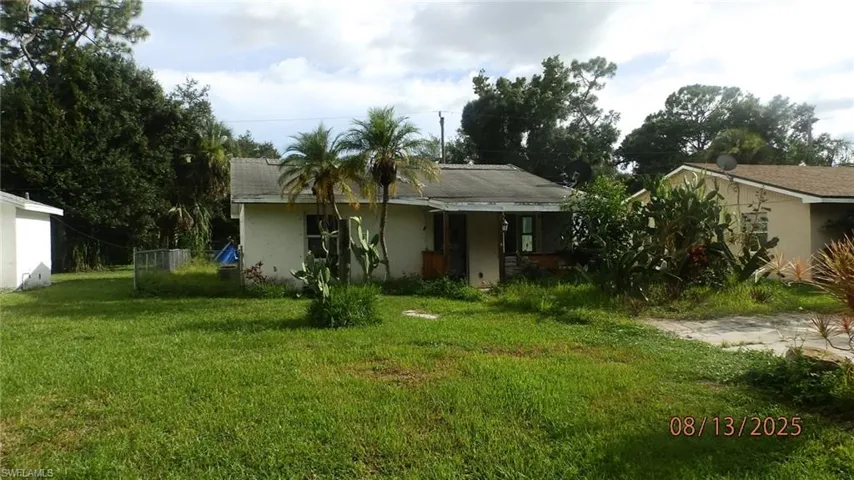 Back of house with stucco siding and a yard