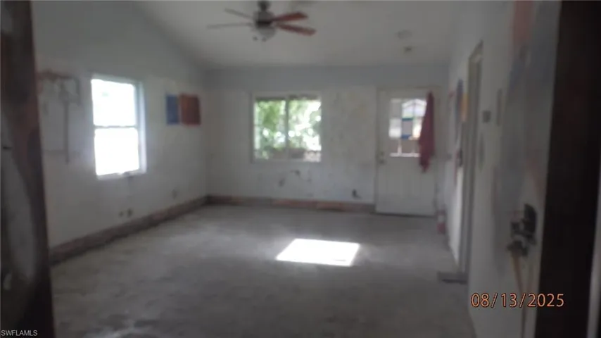 Spare room with lofted ceiling, a ceiling fan, and unfinished concrete flooring