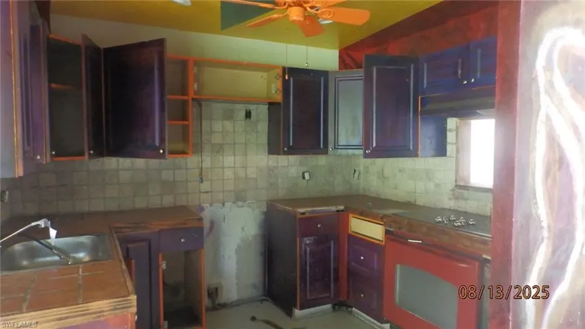 Kitchen with tasteful backsplash, oven, extractor fan, and a ceiling fan