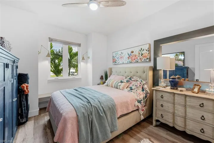 Bedroom with wood-finish flooring, a ceiling fan, and white walls