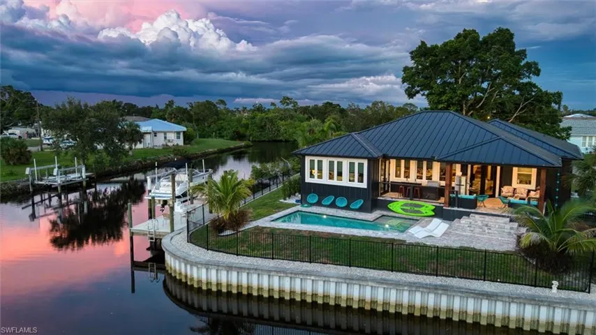Waterfront residence featuring a private dock with boat lift, an in-ground swimming pool, and an expansive patio