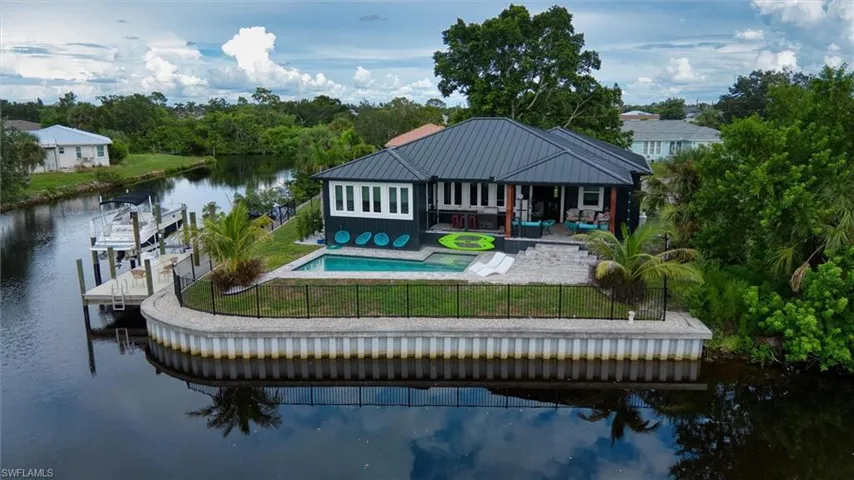Waterfront property featuring a private dock, inground pool, and a metal roof