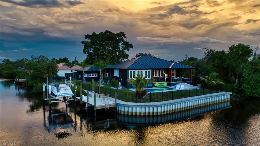 Waterfront property featuring a private boat dock with lift, an in-ground swimming pool, and an outdoor covered patio
