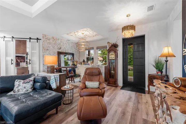 Entryway featuring a modern black door with vertical window, wood-finish flooring, and a decorative ceiling light fixture