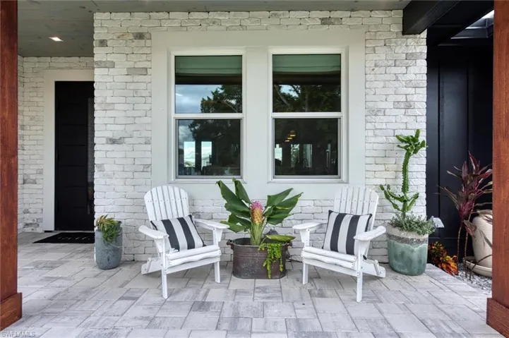 Covered front porch featuring a white brick facade and wood-finish ceiling