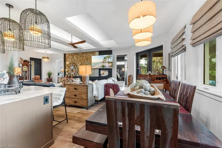 Open-concept living space featuring wood-finish flooring, a tray ceiling with recessed lighting, and a stone accent wall