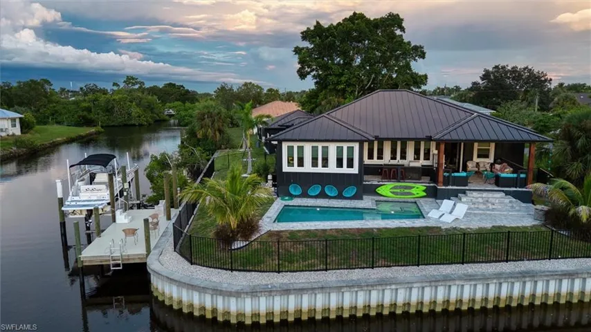 Waterfront property featuring a private boat dock with lift, an inground swimming pool with an integrated spa, a metal roof, and a screened outdoor living area