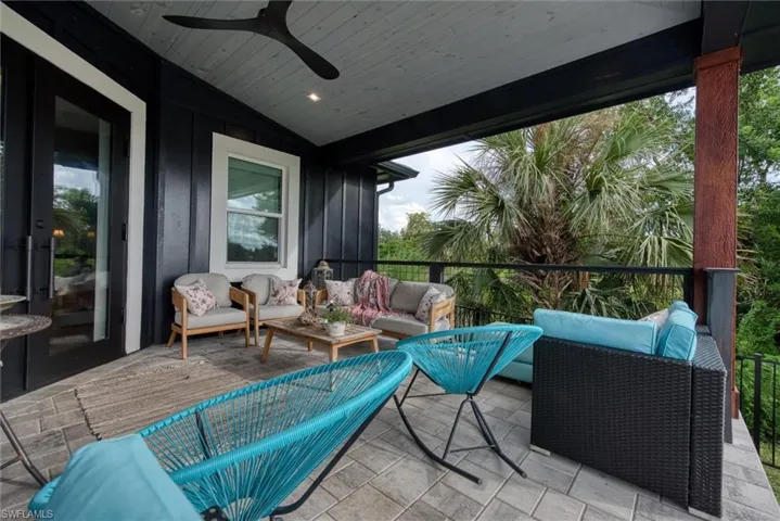 Covered outdoor patio featuring paver flooring, a wood-finish ceiling with a ceiling fan, and black vertical siding