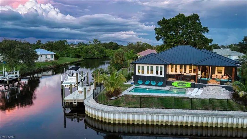 Waterfront residence featuring a private boat dock with lift, an in-ground swimming pool, and an outdoor living area