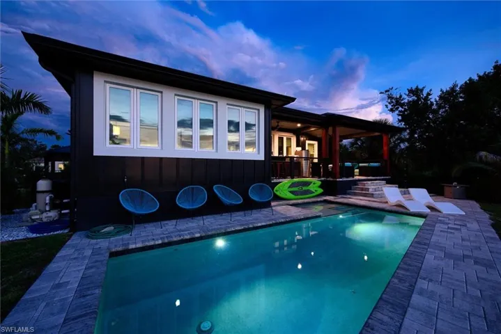Modern exterior with a black and white facade, a private swimming pool, paver decking, and an elevated covered patio