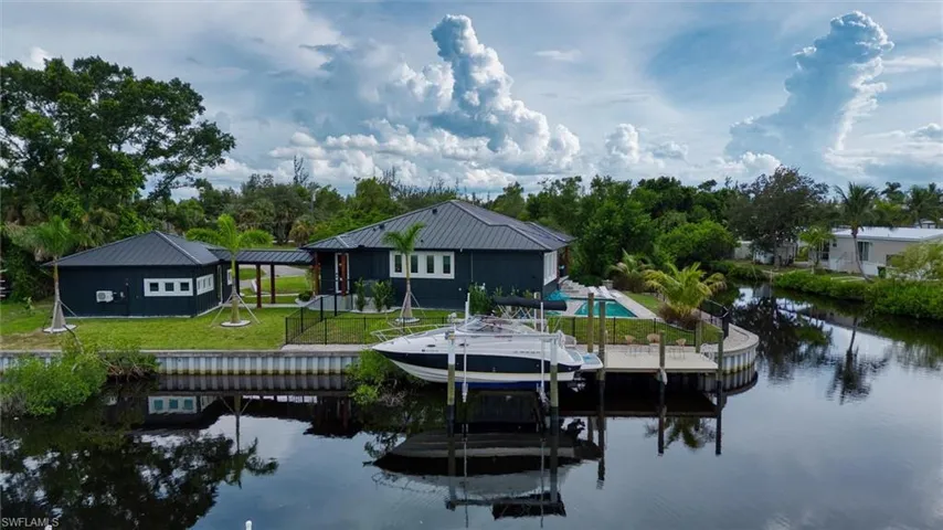 Waterfront property featuring a private dock, swimming pool, detached structure, covered walkway, and metal roofs