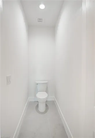 Bathroom featuring toilet and marble finish flooring