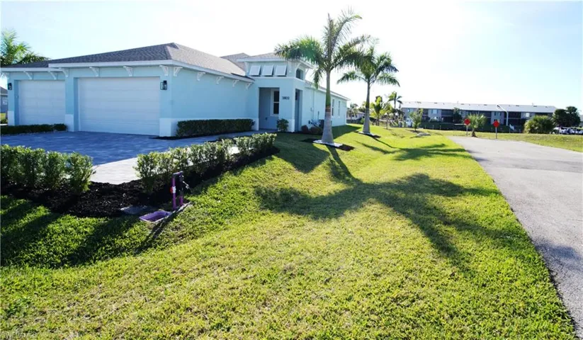 View of front of house featuring driveway, stucco siding, a front yard, and an attached garage