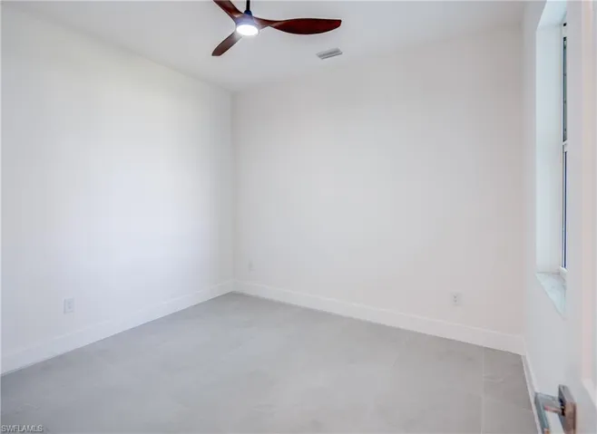 Empty room featuring ceiling fan and baseboards