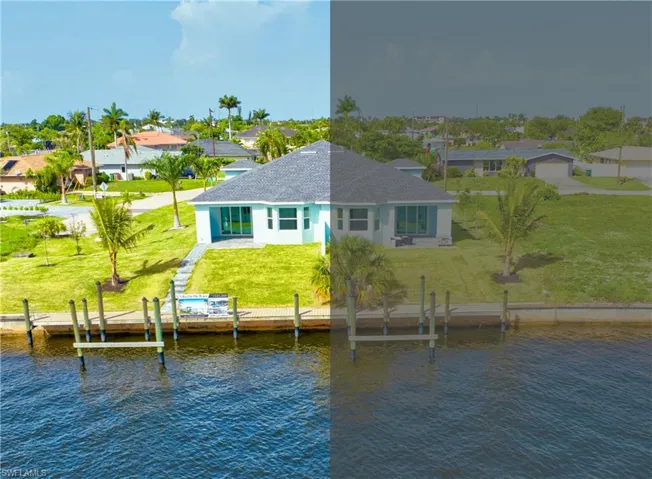Back of property featuring a water view, a shingled roof, a lawn, and stucco siding