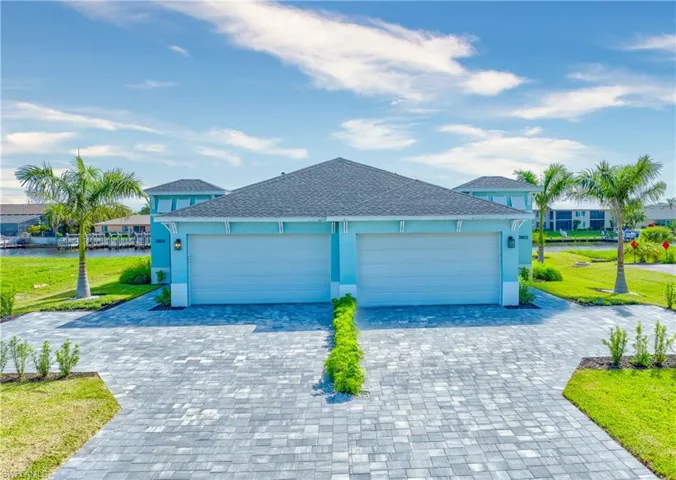 View of front facade featuring a water view, stucco siding, an attached garage, and decorative driveway