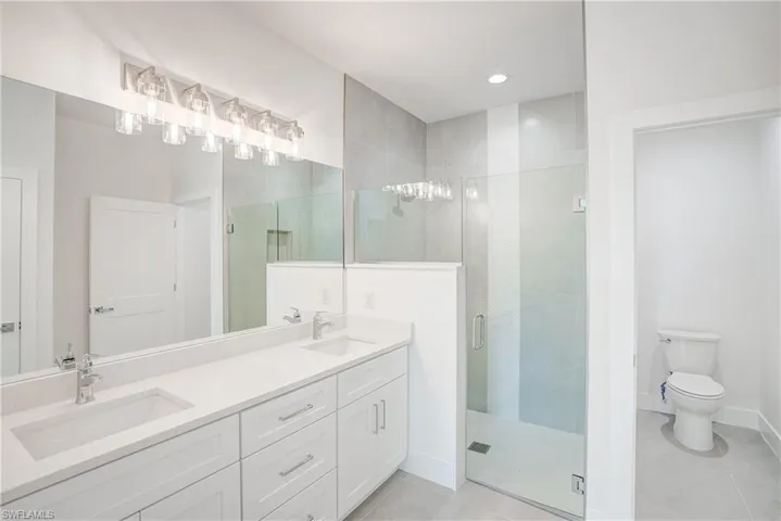 Full bathroom featuring a shower stall, double vanity, tile patterned floors, and recessed lighting