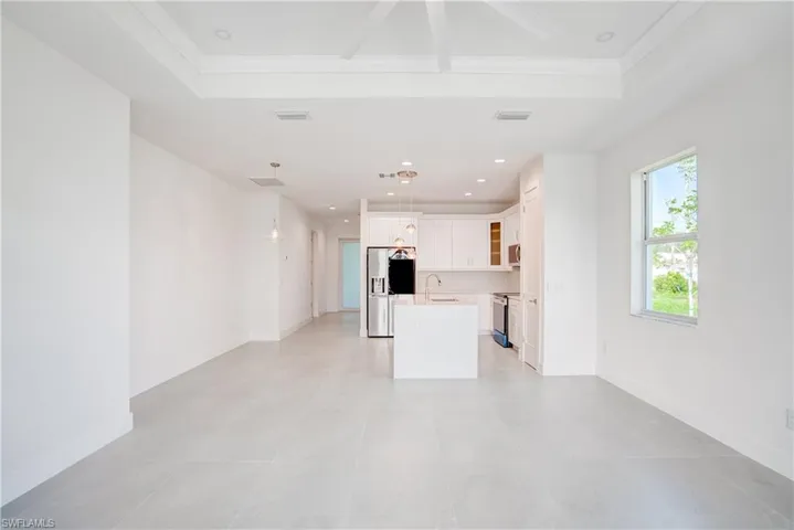Unfurnished living room with a tray ceiling, crown molding, and recessed lighting