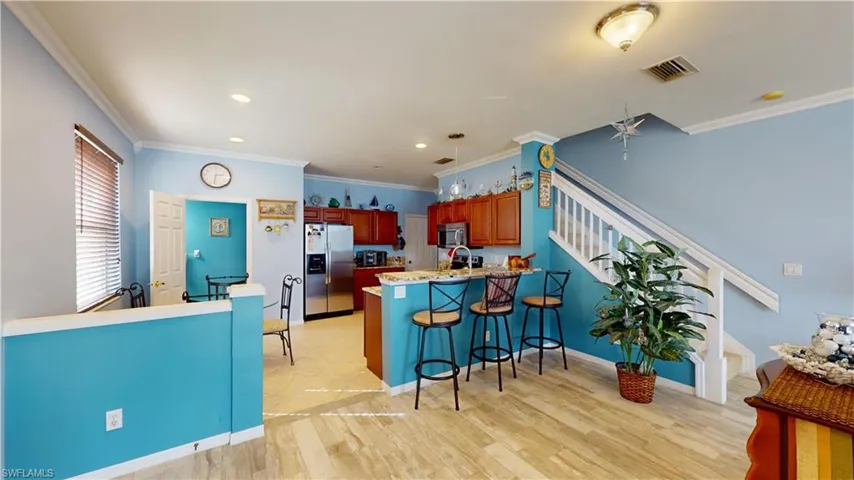 Kitchen with ornamental molding, kitchen peninsula, light wood-type flooring, and stainless steel appliances