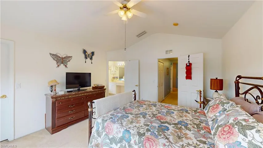 Carpeted bedroom featuring ensuite bath, lofted ceiling, and ceiling fan