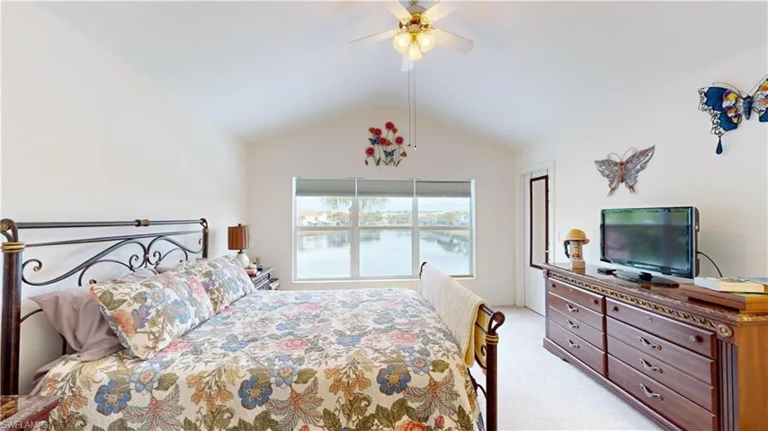 Bedroom featuring light carpet, ceiling fan, and vaulted ceiling
