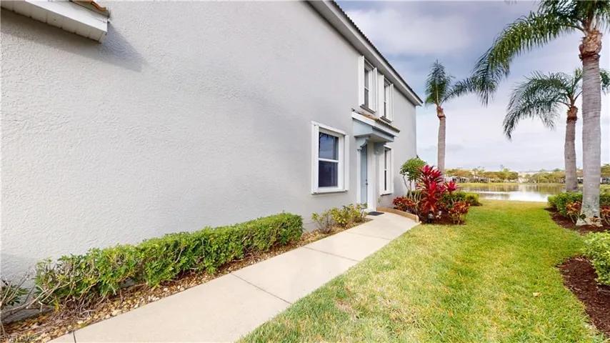 View of side of home featuring a water view and a yard